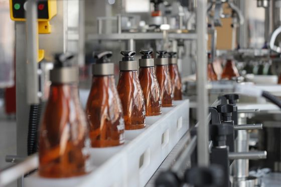 Máquina tampando da garrafa plástica do detergente líquido